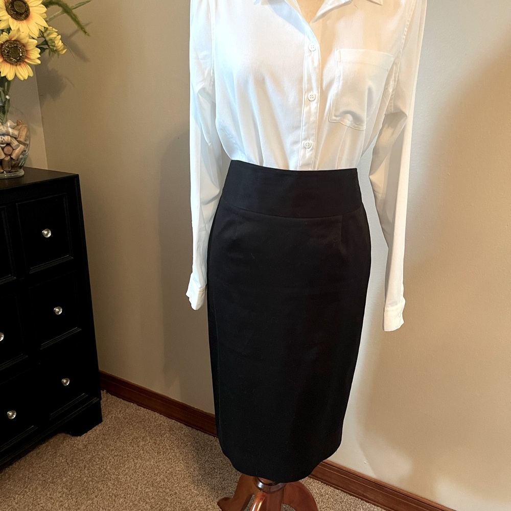 Black knee-length pencil skirt with shaped waist and back kick pleat.